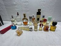 Lot of multiple assorted perfume bottles laid out on white background, front view with labels and caps visible.