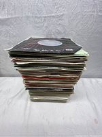 Stack of approximately 125 7-inch vinyl records in original paper sleeves showing thickness and quantity.