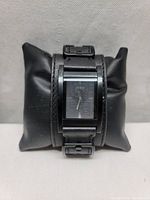Front view of men's Guess wristwatch showing black rectangular case and dial on black leather strap.