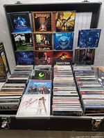 Open hard carry case displaying rows of CD cases with mounted display of 12 soundtrack cover art titles