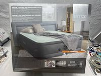 Box front showing the elevated airbed with bedding and description of features, including built-in pump and queen size.