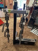 Front view of black metal bike rack with adjustable strapped holders for bikes, showing the bike securing straps hanging from the horizontal bar.