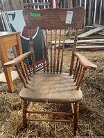 Front view of wooden press back chair showing overall structure, armrests, seat and legs with spindle detailing.