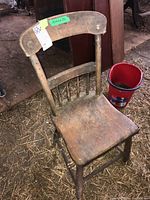 Full view of vintage wooden chair showing seat, backrest with spindles, and legs with signs of dirt and wear.