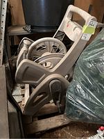 Side view of weathered plastic hose reel showing handle, crank, and spool drum.