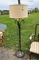 Full view of the metal floor lamp outdoors showing its height and round beige fabric shade