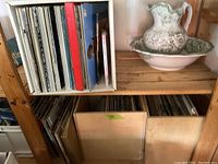 Three wooden boxes filled with vinyl LP records placed on shelves, some boxes visible with multiple records packed inside, upright and closely arranged.