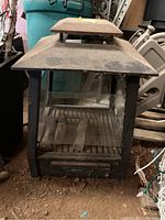 Front view of square metal outdoor fireplace showing the glass panels and inner fire grate.