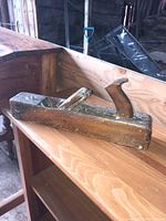 Vintage wooden hand plane positioned on wooden furniture in barn/shed.