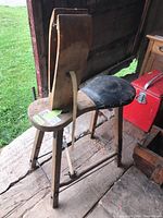 Side view of the wood and leather saddle making stand showing leather saddle and angled wood legs.
