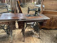 Full view of the antique Singer sewing machine in wooden cabinet with treadle base and drawers visible.