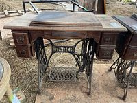 Front view of the antique Singer sewing machine cabinet with cast iron base and drawers.