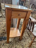 Full view of wooden end table with one drawer and lower shelf, showing its structure and condition.