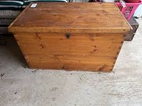 Full frontal view of the closed wooden trunk showing its rectangular shape and natural wood finish.