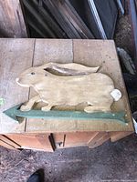 Full view of wooden weather vane featuring a rabbit figure with a green arrow base.
