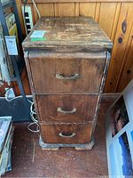 Front view of the wood cabinet showing three drawers with metal handles and worn finish.