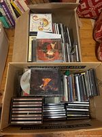 Box of classical music CDs and cassette tapes arranged upright and stacked horizontally showing multiple cases and collection variety.