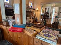 Wide view of games and toys including Orbito board game, domino sets, and chess/checker boards on cabinet