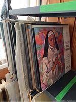 Rows of classical LP albums and boxed sets standing vertically on a shelf. Visible album titles include Puccini Suor Angelica and others. Album covers show wear and some damage.