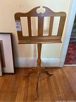 Front view of wooden music stand showing the decorative top cutout and the music ledge with three vertical slats.