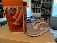 Nike Air running shoes size 10.5 and box for Sanyo electric heated slippers displayed on table.