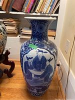 Front view of the tall blue and white Asian porcelain vase showing seated figures.
