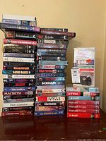 Stack of over 40 VHS movie tapes mixed with blank VHS tapes and a VCR head cleaner tape.