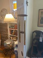 Full view of wind chime hanging near bookshelf and large pottery.