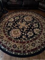Round Persian rug laid out on hardwood floor. Shows central floral medallion and border patterns.