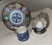 All three pieces on white background: Imari plate, phoenix cup, dragon stand with egg