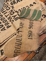 Close-up photo showing the burlap Christmas stocking with green stripes and printed text over an authentic Ethiopian burlap coffee bag with printed black text.