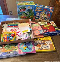View of board games Gator Golf, Gone Fishin', Bingo, a box filled with scrapbook materials including stickers and activity sheets, plus puzzles including a Disney 400 piece puzzle.