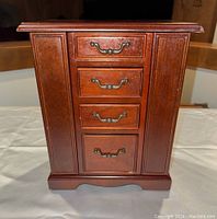 Front view showing four drawers with decorative metal handles and two side vertical panels