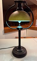Front view of the bronzed table/library lamp, showing the entire lamp standing on a flat surface with its power cord visible.