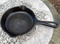 Top view of cast iron skillet showing cooking surface, pouring spouts, and handle.