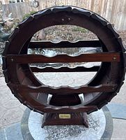 Front view of handcrafted wooden wine rack showing circular barrel shape and three horizontal grooved bottle supports.