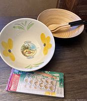 Photo showing all items in the lot: ceramic pasta bowl with sunflower and Italian landscape design, wooden salad bowl with utensils, and boxed VillaWare ravioli maker with recipes.