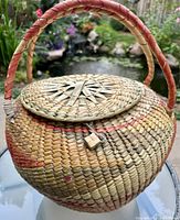 Photo showing the top view of the basket with lid and woven toggle closure, double handles wrapped in colored fibers.