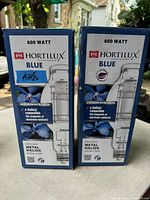 Two boxed Hortilux 600 watt blue daylight metal halide grow lamps shown side by side outdoors.