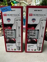 Photo of two boxed Hortilux 600 watt Ceramic HPS grow lamps with red spectrum, showing front packaging.