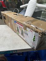 Box of the artificial Christmas tree with shipping labels and tape, showing the size and packaging condition.