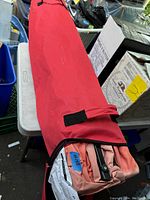 Photo of the gazebo fabric and frame folded inside a red carrying bag with zipper.