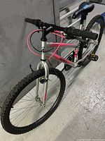 Front and side view of the Movelo 26-inch mountain bike showing frame, tires, handlebar, and pink brake cable.