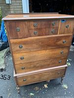 Front view of antique highboy dresser showing eight drawers and casters