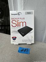 Photo of Seagate Backup Plus Slim 1TB portable external hard drive box showing front with branding and capacity