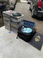 Large stacks of CDs displayed on table with visible titles and multiple genres starting with country, pop, rock.