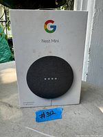 Front of original box showing Google logo, Nest Mini name and image of the 2nd generation smart speaker with white power cable.