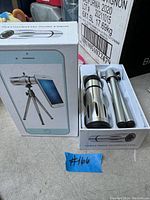 Mobile phone telephoto lens and tripod kit in white box with fitted insert, lens and tripod shown inside.