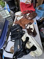 Wide view of nine vintage purses on a table, showing various styles and materials including leather, fabric, and suede in black, brown, white, and red.
