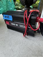 Side view of power inverter showing brand label and power cables with red protective caps.